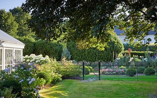 Mary Berry's Henley garden in summer with estate fencing, hydrangeas and lawn 