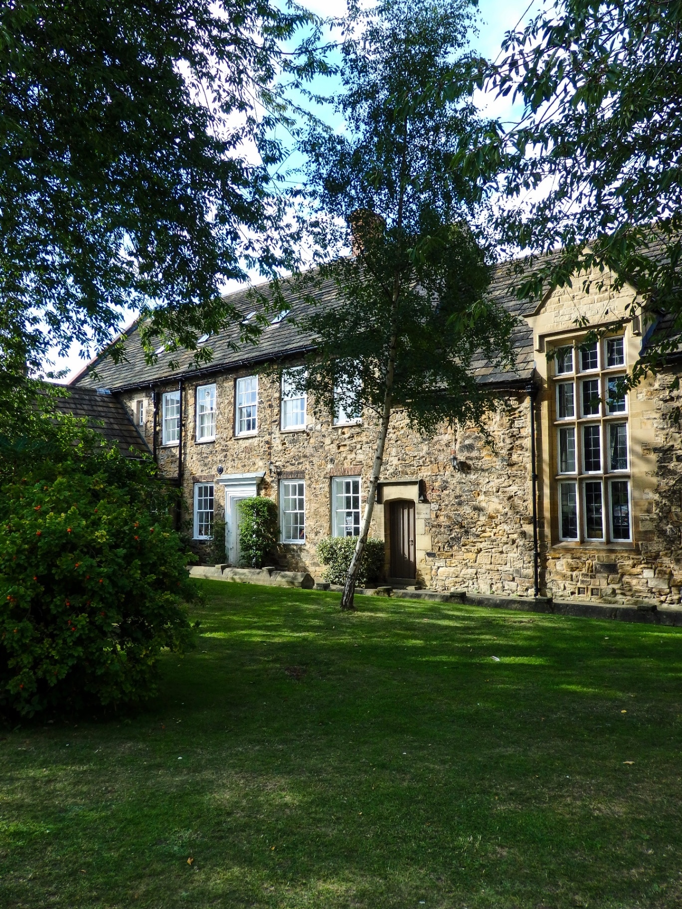 Beautiful honeycomb stone house with shady trees during the English summer in Durham, England