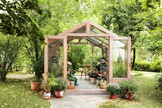 Interior of a wooden illuminated greenhouse with furniture