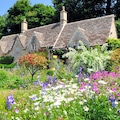 English Country Cottage with beautiful flowers garden in the sunshine in Cotswolds, England, UK